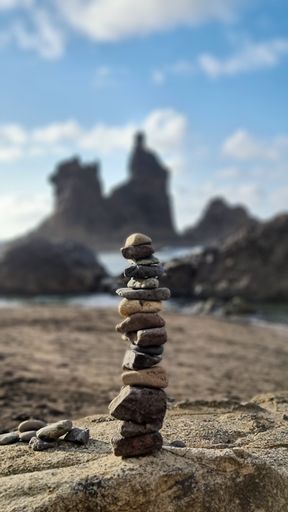 A vertical shot of tiny rocks stacked on top of each other at the beach with a blurry background