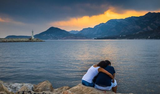 A lovely couple hugging each other near a seaside during sunset