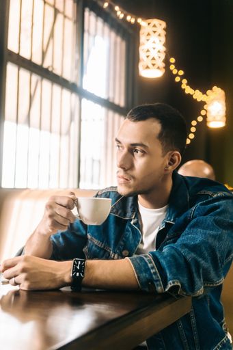 An attractive young Hispanic man having a cup of coffee in a restaurant
