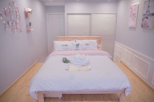 Cozy bedroom interior with soft pastel decor, a neatly made bed, and wooden flooring, creating a serene and inviting atmosphere.