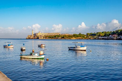 A closeup shot of  fishing boats on the Malecon in Havana, Cuba Morro castle in the background