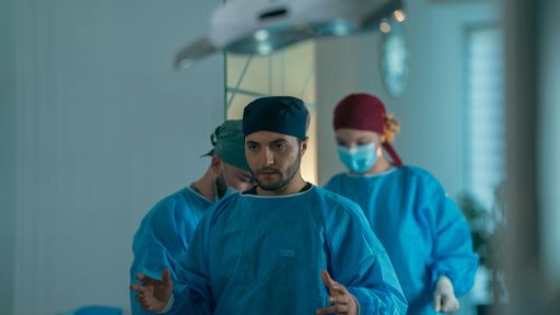 Medical team in surgical attire focused during a procedure in a hospital operating room.