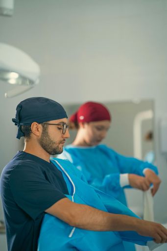 The two surgeons in a hospital preparing for surgery, wearing blue and red caps, focused on their tasks