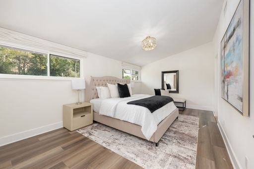 Modern bedroom interior with elegant decor, featuring a plush bed, large windows, and contemporary artwork.