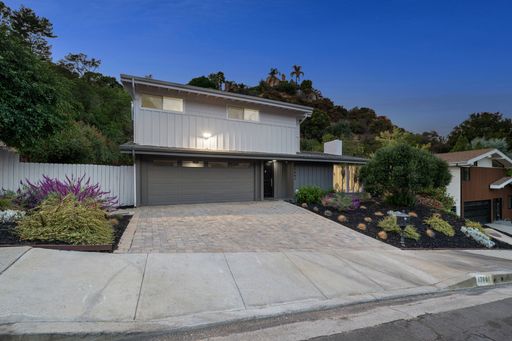 Modern suburban house with landscaped front yard and driveway in a residential neighborhood at dusk.