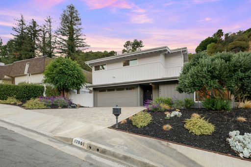 Modern suburban house with landscaped front yard and a vibrant sunset sky.