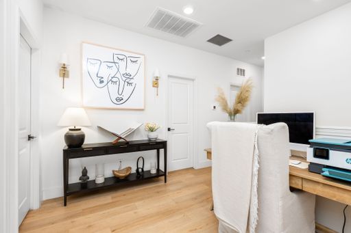 Modern home office with minimalist decor, featuring a desk, chair, and wall art, creating a stylish and functional workspace.
