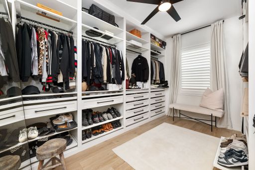 Modern walk-in closet with organized clothing, shoes, and accessories, featuring a sleek design and ample natural light.
