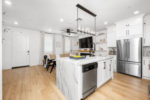 Modern kitchen interior with marble island, stainless steel appliances, and wooden flooring in a bright, contemporary home setting.