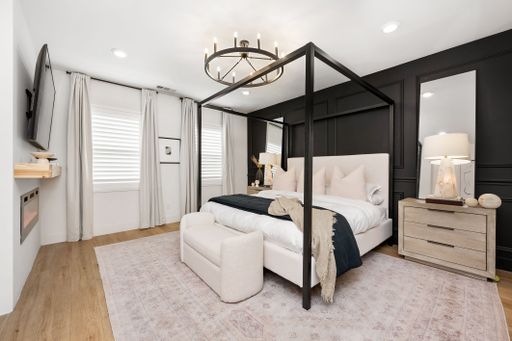 Elegant modern bedroom with a four-poster bed, black accent wall, and cozy lighting, showcasing contemporary interior design.