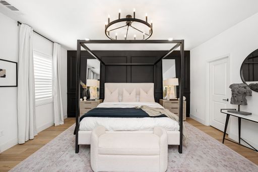 Modern bedroom interior with a canopy bed, elegant chandelier, and minimalist decor, featuring neutral tones and natural light.