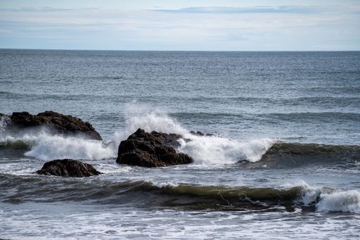 Waves crashing against rocky shores under a cloudy sky, capturing the dynamic beauty of the ocean.