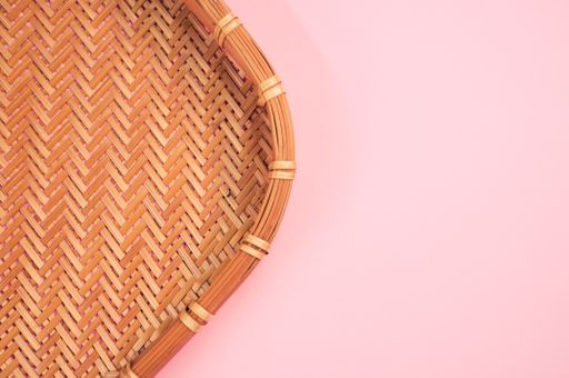A top view of bamboo wicker tray isolated on pink background