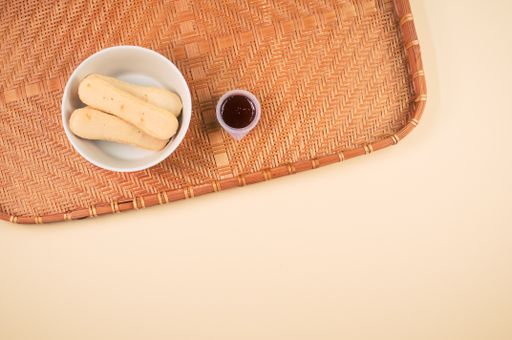 A high angle shot of a bowl of cookies and jam on a woven fabric on an orange surface