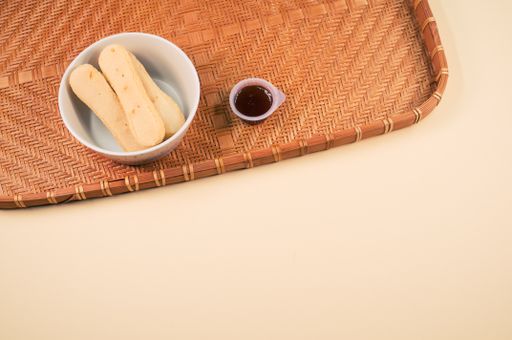 A high angle shot of a bowl of cookies and jam on a woven fabric on an orange surface