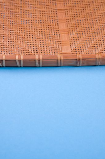 A vertical shot of bamboo wicker tray isolated on brown background