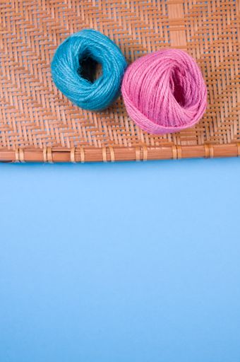 A vertical shot of blue and pinyarn on bamboo wicker tray isolated on blue background