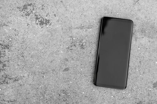 A top view of a modern black smartphone on the concrete ground - space for text