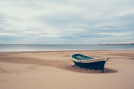 A green wooden boat on a sand seashore