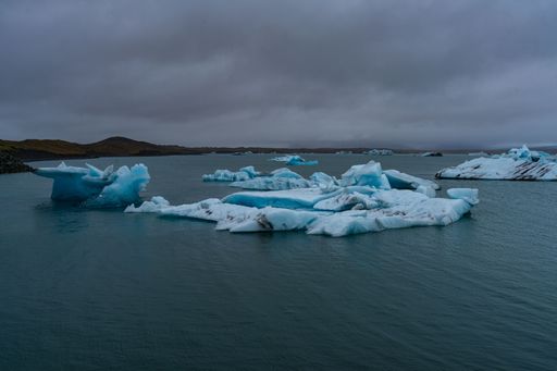 Scenic view of icebergs floating in Jokulsarlon Glacier Lagoon, Iceland, under a cloudy sky.