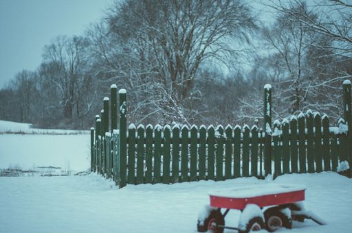 A selective focus shot of a wooden fence covered with white snow during winter