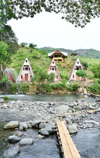 A vertical shot of three small colorful cottages on a riverbank in Indonesia