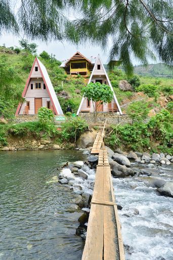 A vertical shot of two small colorful cottages on a riverbank in Indonesia