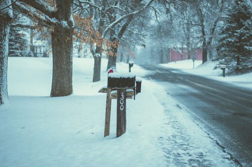 A shallow focus shot of a mailbox at the side of the road covered with white snow during winter