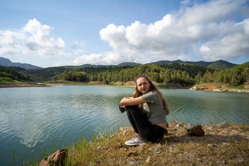 A young woman sitting near the lake on a sunny day