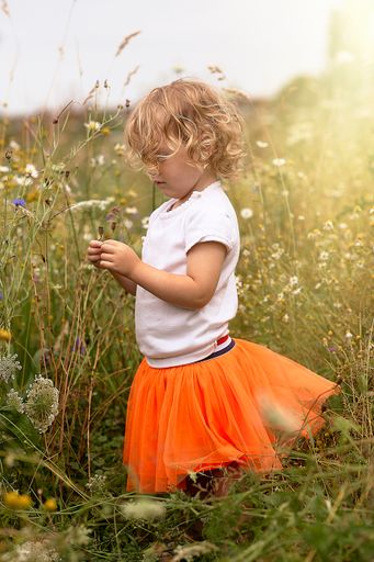 A vertical shot of a cute blonde child playing on a meadow