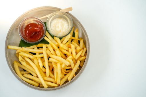 An overhead shot of french fries with mayo and ketchup on a plate