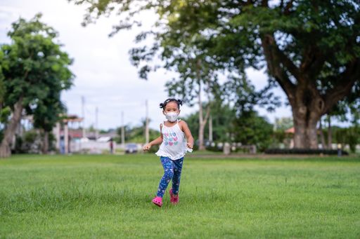 A beautiful southeast Asian female kid running on a lawn