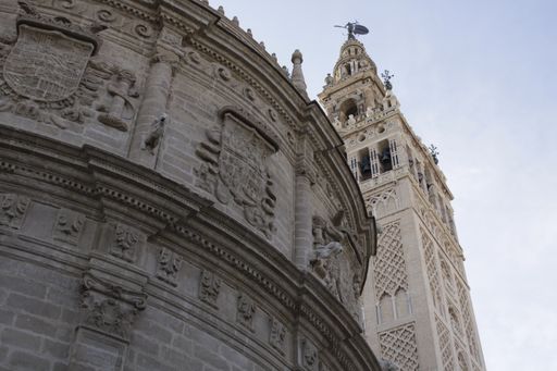 A low angle shot of the Giralda bell tower of the Seville Cathedral against a bright sky