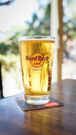 A vertical shot of cold Hard Rock Cafe beer on a woody brown table in Angkor Wat, Thailand