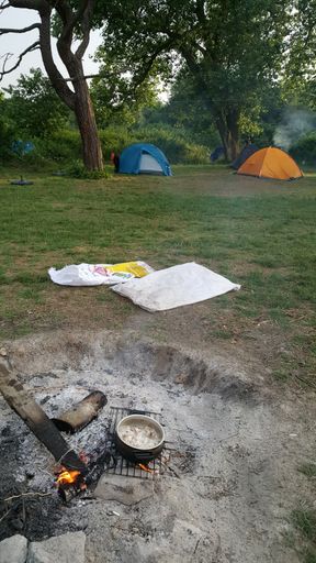 A vertical shot of a burnt out fire on a hillside camping ground