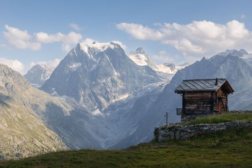 Summer landscape view of a typical Swiss chalet in front of the snow-capped Mont Collon mountain peak