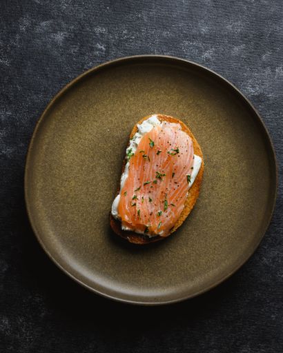 A vertical top view of a plate with delicious salmon toast on it on a rustic gray table