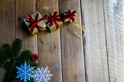 A top view of gift boxes, fir branches, and snowflakes on a wooden table