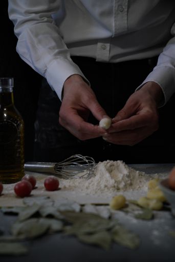 A vertical shot of a person with a piece of dough in his hands over the flour