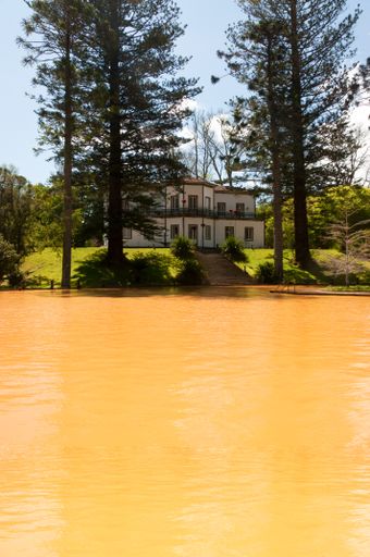 A vertical picture of a hot pool surrounded by greenery under the sunlight in Furnas in Portugal