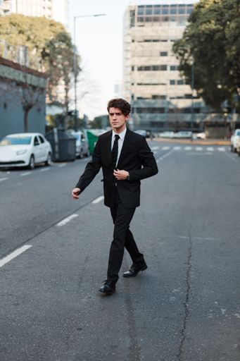 A vertical shot of a serious young Caucasian guy dressed professionally walking on a street