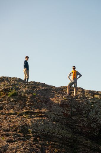 A vertical shot of two men on a rocky cliff in Portland