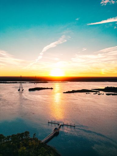 A breathtaking sunset over a serene lake with a pier, vibrant sky, and tranquil waters.