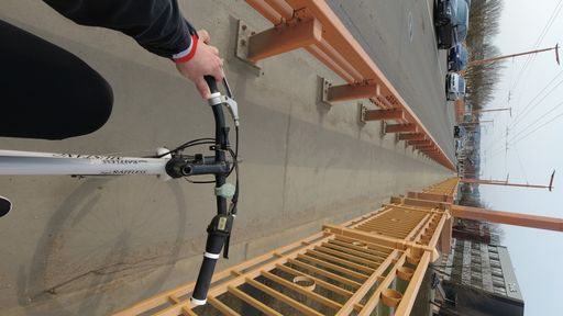 A vertical pov shot of a young man riding a bike on the yellow bridge in Kaunas, Lithuania