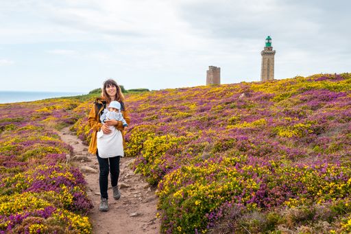 A mother and her baby posing on a meadow near the Phare Du Cap Frehel lighthouse in  France