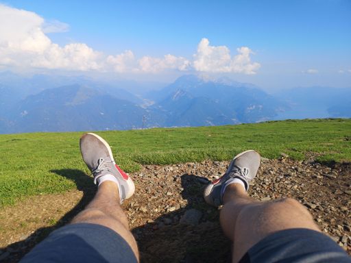 A closeup shot of male stretched legs on the ground in a green field on a sunny day