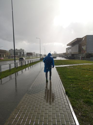 A vertical shot of a male walking in the street in city on a rainy day