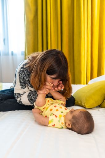 A vertical shot of a young Caucasian mother and her adorable baby playing on a bed
