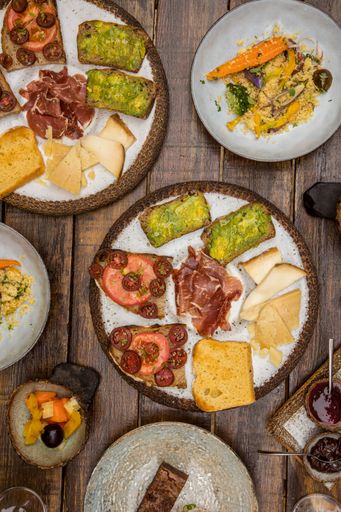 A vertical top view shot of plates with snacks and toasts with vegetables and other snacks