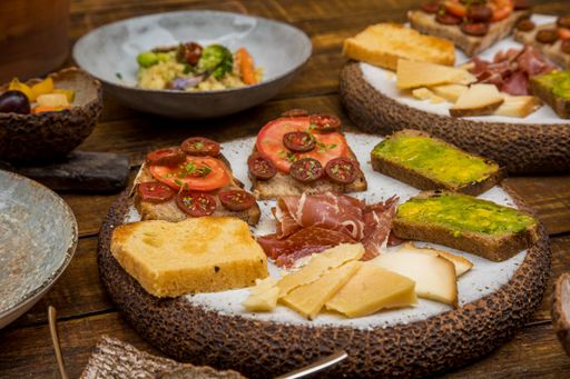A closeup shot of servings with toasts, salads, and fruits on a wooden table